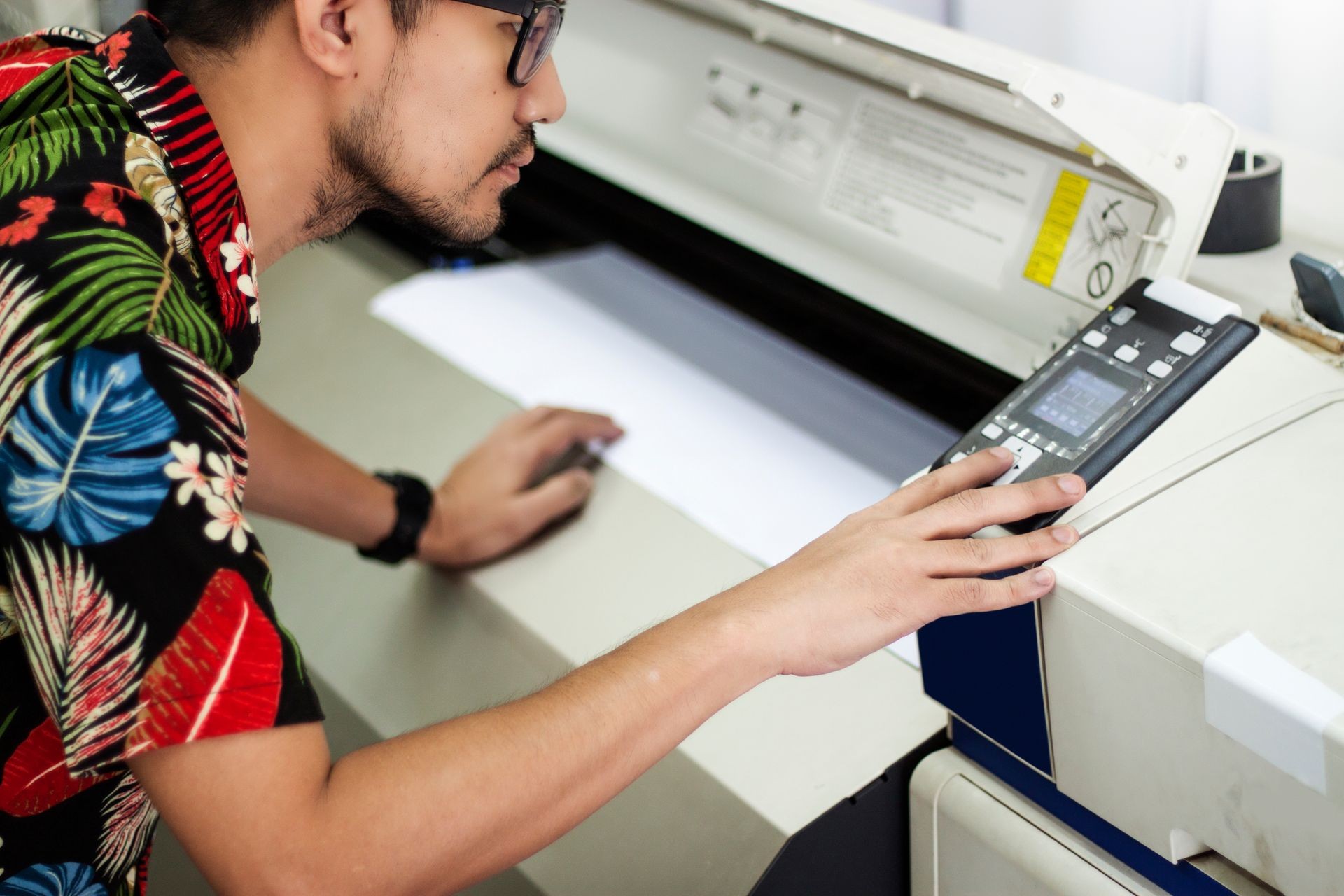 Asian male employee Checking the printer for printing For delivering customers He is setting up the printer to choose the right material for the job.